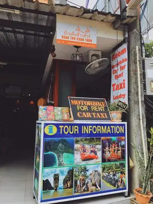 a sign in front of a restaurant with a sign for a tour information at Baantonkhaokata Hotel in Kata Beach