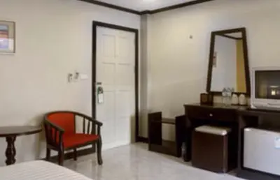 a bedroom with a bed and a desk and a mirror at Baantonkhaokata Hotel in Kata Beach