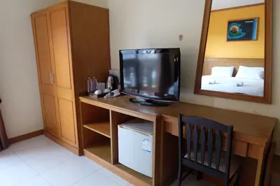 a room with a desk with a television and a bed at Baantonkhaokata Hotel in Kata Beach