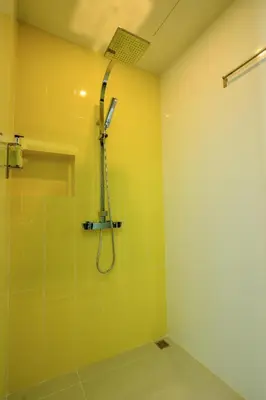 a bathroom with a shower in a yellow wall at Wake Up Aonang Hotel in Ao Nang Beach