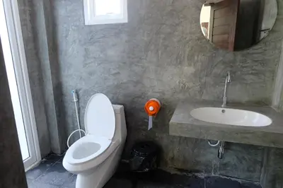 a bathroom with a toilet and a sink and a mirror at Maikhao Beach Guest House in Mai Khao Beach