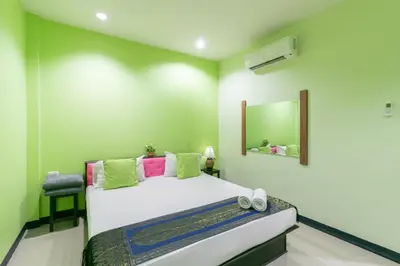 a bedroom with a bed with a mirror and a chair at Chaiyo Resort in Phuket Town