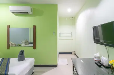 a room with a green wall with a tv and a couch at Chaiyo Resort in Phuket Town