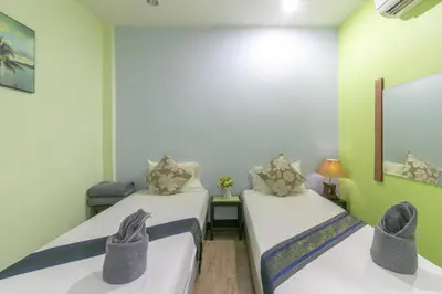 two beds in a room with green walls at Chaiyo Resort in Phuket Town