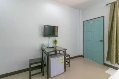 a room with a refrigerator and a tv on a wall at Chaiyo Resort in Phuket Town