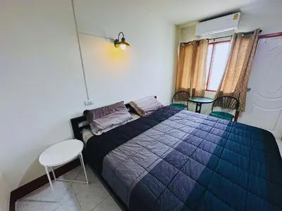 a bedroom with a bed with a blue comforter and a chair at K.L.Apartment in Chalong