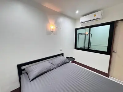 a bedroom with a bed with a window and a bed at K.L.Apartment in Chalong