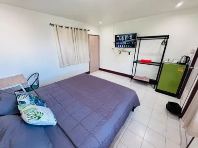 a bedroom with a blue bed and a tv at K.L.Apartment in Chalong
