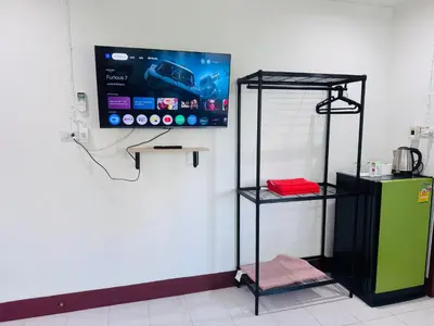 a room with a tv on the wall and a shelf at K.L.Apartment in Chalong
