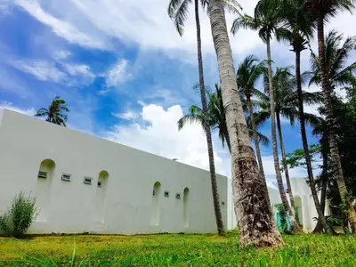 a white building with palm trees in front of it at Sense of Yanui in Nai Harn Beach