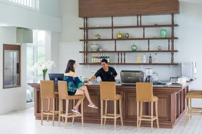 a man and woman sitting at a bar in a kitchen at Panphuree Residence in Nai Yang Beach