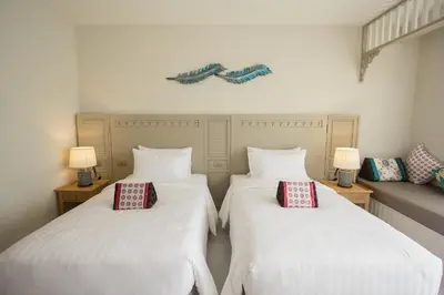 two beds in a room with white sheets and red pillows at Panphuree Residence in Nai Yang Beach