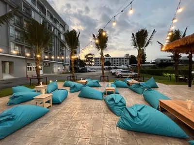 a patio with blue pillows and tables and a building at Panphuree Residence in Nai Yang Beach