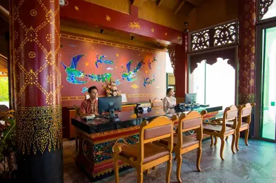 two people sitting at a table in a restaurant at Maikhao Palm Beach Resort - SHA Plus in Mai Khao Beach