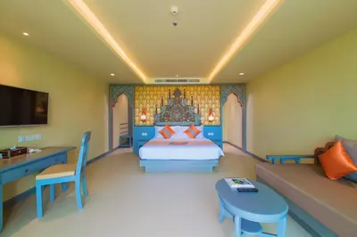 a bedroom with a bed and a couch at Maikhao Palm Beach Resort - SHA Plus in Mai Khao Beach