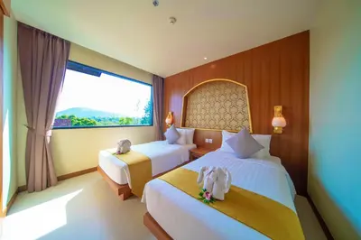a bedroom with two beds and a large window at Maikhao Palm Beach Resort - SHA Plus in Mai Khao Beach