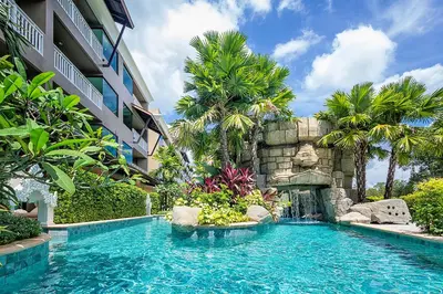 a swimming pool in a resort with a waterfall at Maikhao Palm Beach Resort - SHA Plus in Mai Khao Beach