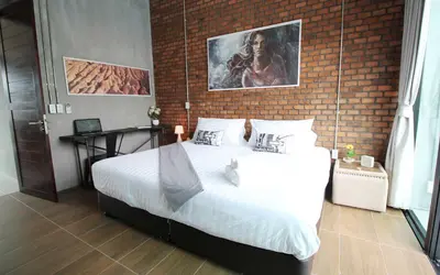 a bedroom with a large bed with a brick wall at Unique Loft Apartment in Kamala Beach