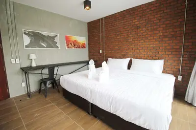 a bedroom with a large white bed with a brick wall at Unique Loft Apartment in Kamala Beach