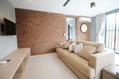 a living room with a couch and a brick wall at Unique Loft Apartment in Kamala Beach