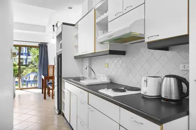 a kitchen with white cabinets and a black counter top at The Club Residence Kamala Beach in Kamala Beach