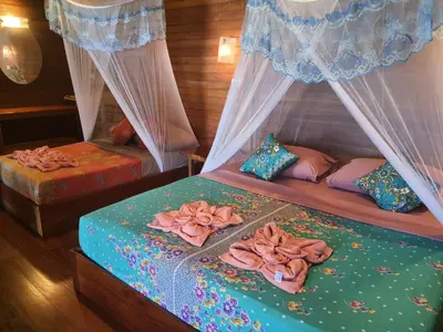 a bedroom with two beds with curtains and towels on them at Sabai Corner Bungalows - SHA Extra Plus in Ko Yao Noi