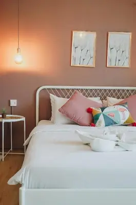 a bedroom with a white bed with pink walls at Thira House in Karon Beach