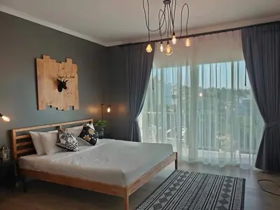 a bedroom with a large bed and a large window at Thira House in Karon Beach