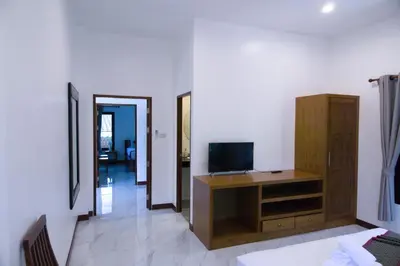 a living room with a television on a wooden cabinet at Chanapha Residence in Tab Kaek Beach