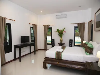 a bedroom with a bed and a tv in it at Chanapha Residence in Tab Kaek Beach