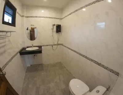 a white bathroom with a toilet and a sink at Chanapha Residence in Tab Kaek Beach