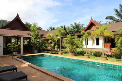 a villa with a swimming pool in front of a house at Chanapha Residence in Tab Kaek Beach