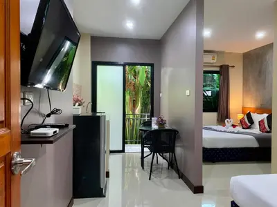 a bedroom with a bed and a television and a table at Isayarada Apartment in Thalang