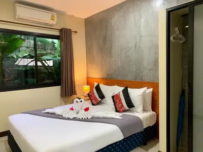 a bedroom with a large bed with white sheets at Isayarada Apartment in Thalang