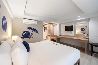 a bedroom with a white bed and a bathroom at Kokotel Phuket Patong in Patong Beach