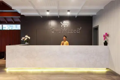 a man standing behind a large white reception desk at Orchidacea Resort - Kata Beach in Kata Beach
