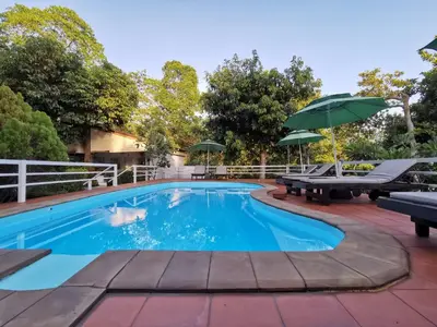 a swimming pool with two benches and an umbrella at On The Hill Karon Resort in Karon Beach