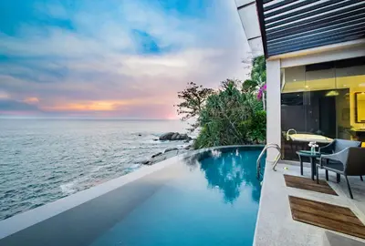 a house with a swimming pool next to the ocean at Impiana Private Villas Kata Noi in Kata Beach