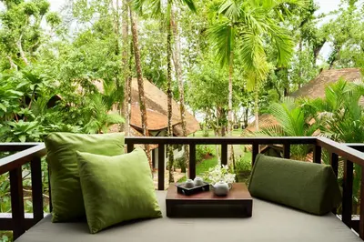 a balcony with green pillows and a table and trees at The Tubkaak Krabi Boutique Resort in Tab Kaek Beach