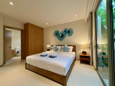 a bedroom with a large white bed with blue pillows at Trichada Villas by RESAVA in Bang Tao Beach