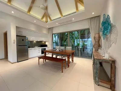 a kitchen with a wooden table and a dining room at Trichada Villas by RESAVA in Bang Tao Beach