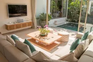 a living room with a couch and a table and a pool at Trichada Villas by RESAVA in Bang Tao Beach