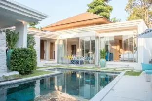 a house with a swimming pool in front of a house at Trichada Villas by RESAVA in Bang Tao Beach