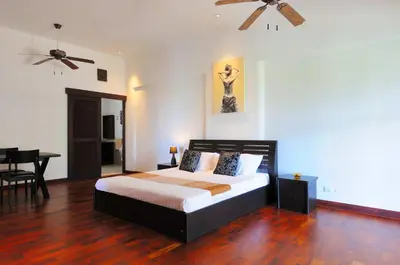 a bedroom with a bed with a ceiling fan at Surin villa in Surin Beach