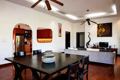 a dining room with a table and a couch at Surin villa in Surin Beach