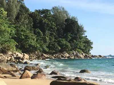 a beach with rocks and the water and trees at Surin villa in Surin Beach