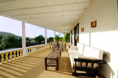 a porch with chairs and tables on a building at Surin villa in Surin Beach