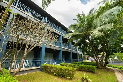 a blue building with palm trees in front of it at Peace Laguna Resort & Spa in Ao Nang Beach