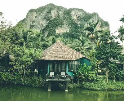 a house on the water in front of a mountain at Peace Laguna Resort & Spa in Ao Nang Beach