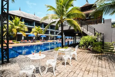 a patio with tables and chairs next to a pool at Ramada by Wyndham Aonang Krabi in Ao Nang Beach